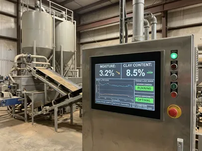 PLC control panel displaying real-time moisture and clay content readings for a clay sand preparation line